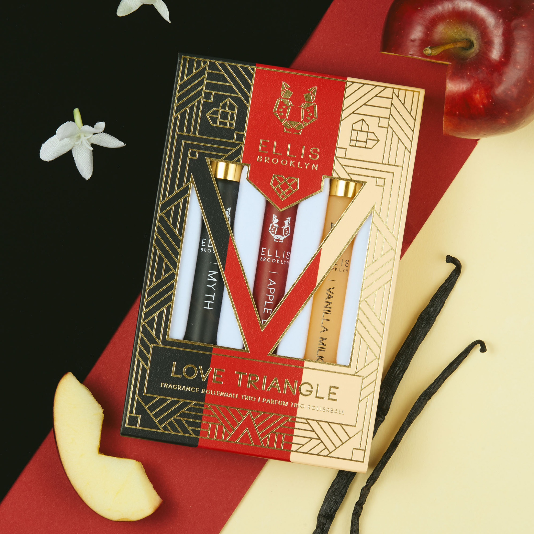 Ellis Brooklyn Love Triangle perfume set with apple slices and vanilla beans on a dark background