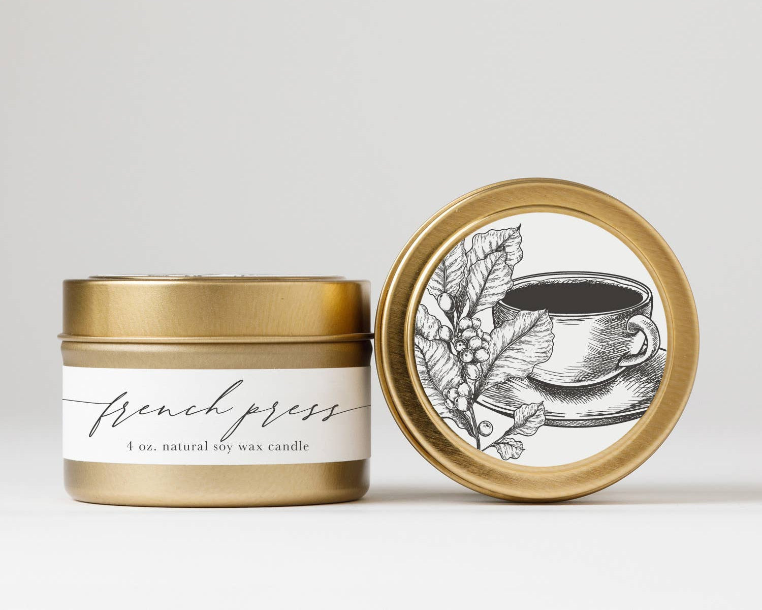 Gold candle jar with white label and decorative lid featuring a coffee cup illustration on a light gray background.