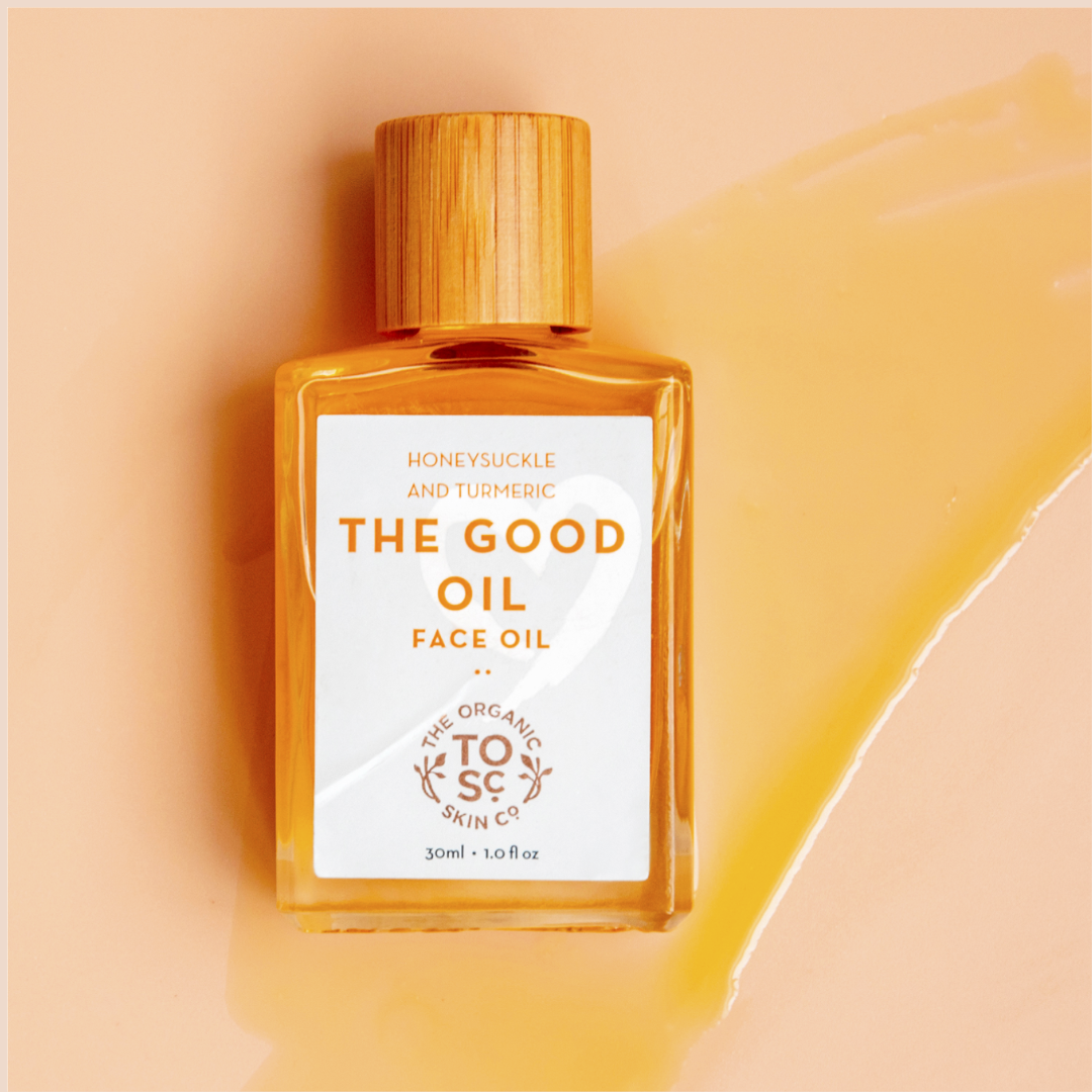 Bottle of 'The Good Oil' face oil with a wooden cap on a peach background